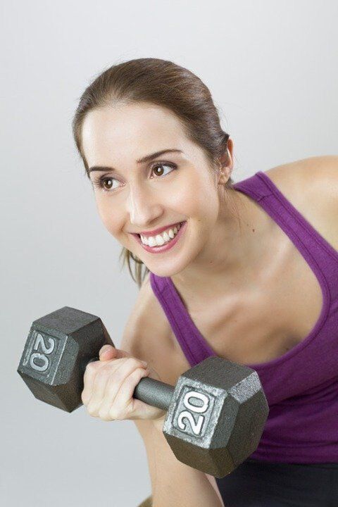 seorang gadis dengan dumbbell melakukan latihan untuk menurunkan berat badan